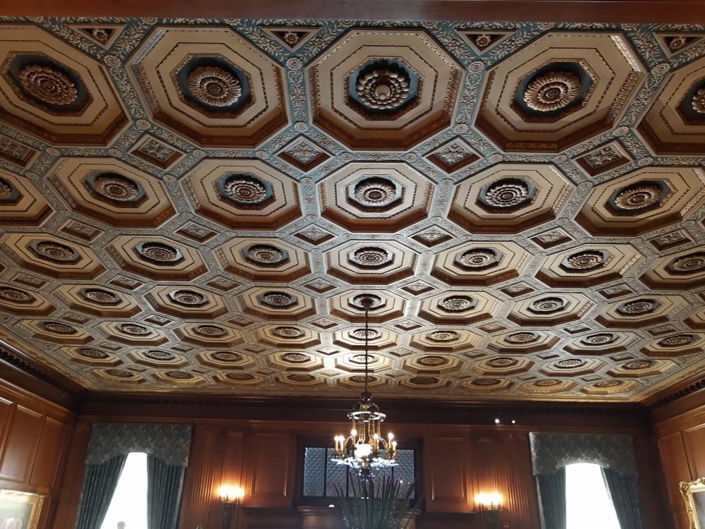 A view of an ornately recessed ceiling and appropriately sized chandelier