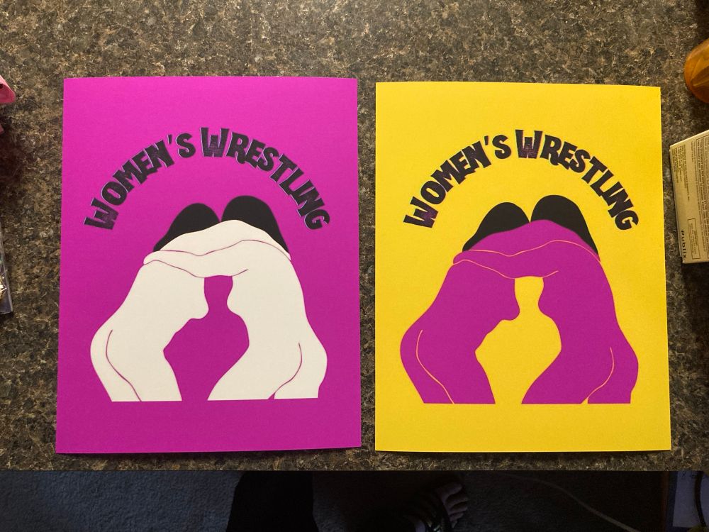 Two variations of the same design printed on 8x10 photo paper. It’s bright/deep berry pink with a design of two abstract women printed in white ink with black hair. They are locked up in a wrestling hold with their arms around each other’s neck/shoulders, but they could also be hugging or kissing. Above the women it says “Women’s Wrestling.” The other print is the same except the background is a goldenrod color, and the women are fuchsia.