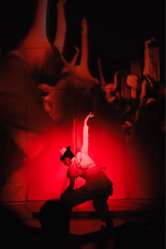 A woman bathed in red light dancing as part of the performance art experience.
