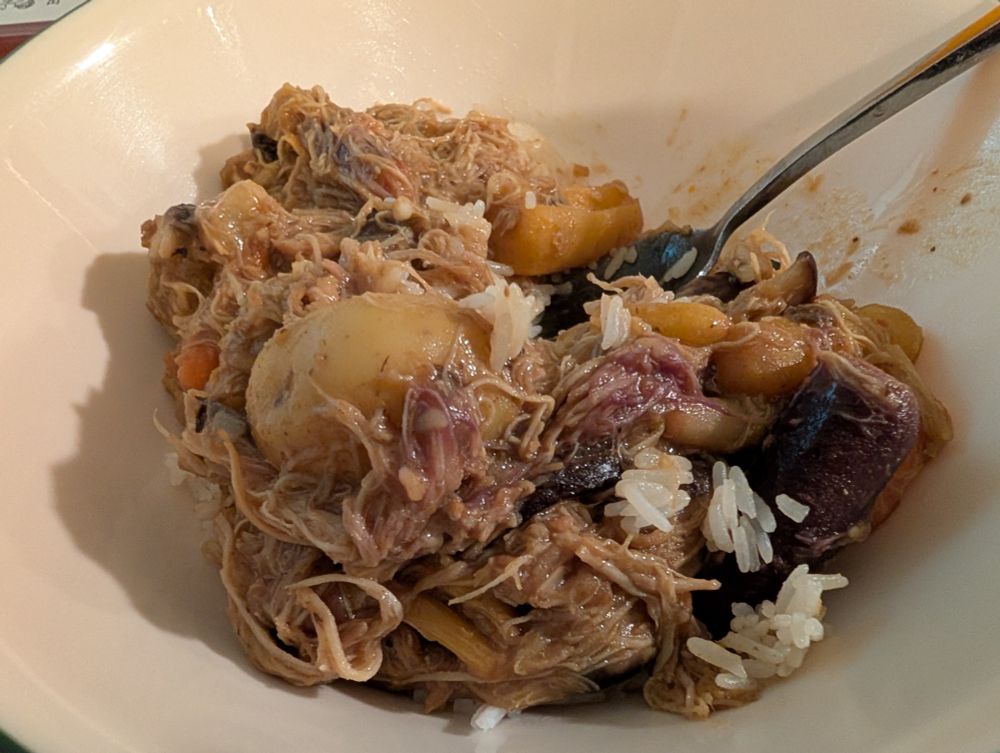 Yellow curry with shredded chicken, baby potatoes, mushrooms, and multicolored carrots. The purple carrots have stained the chicken. It is delicious.