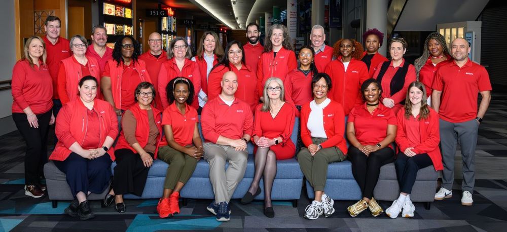 Group of ARVO staff members wearing red shirts, posing for a photo in a corridor.