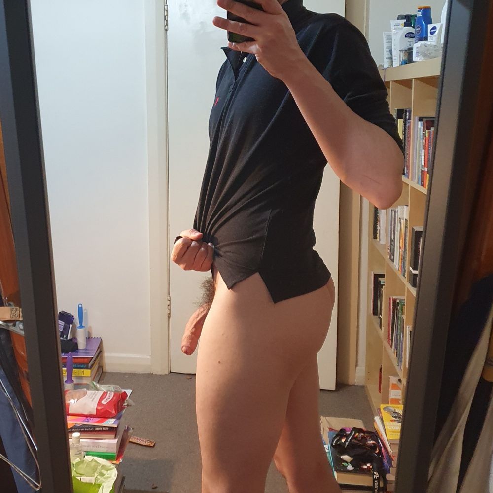 a man taking a body pic selfie, standing in profile so we can see both ass and cock in the same pic. A peek of cock, a curved ass. The top half is covered by a black shirt