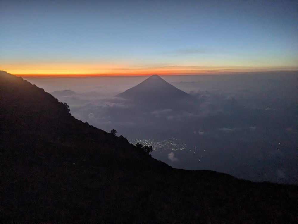 A volcano, seen from above the cloudline at sunrise.