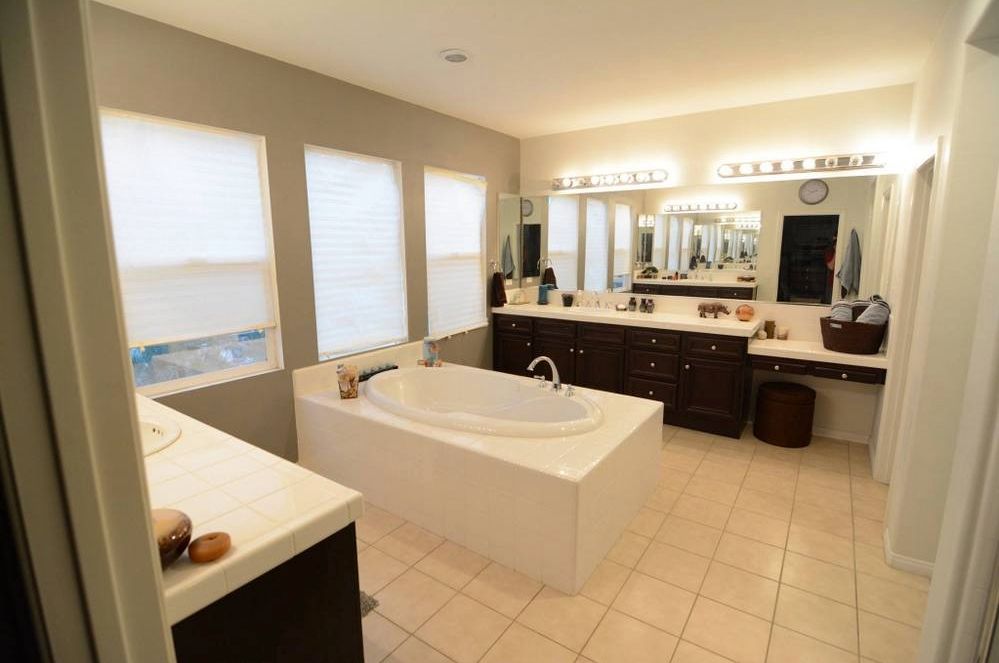 The infamous "Doom Bathroom" by Somethingawful's bEatmstrJ, before pic: a mundane tiled master bathroom with a large tub places between two vanities. Very warm tones.