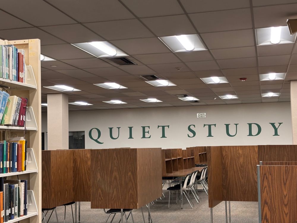 Study carrels in a library with huge vinyl letters saying quiet study in all caps (all caps indicates shouting in internet orthography). 