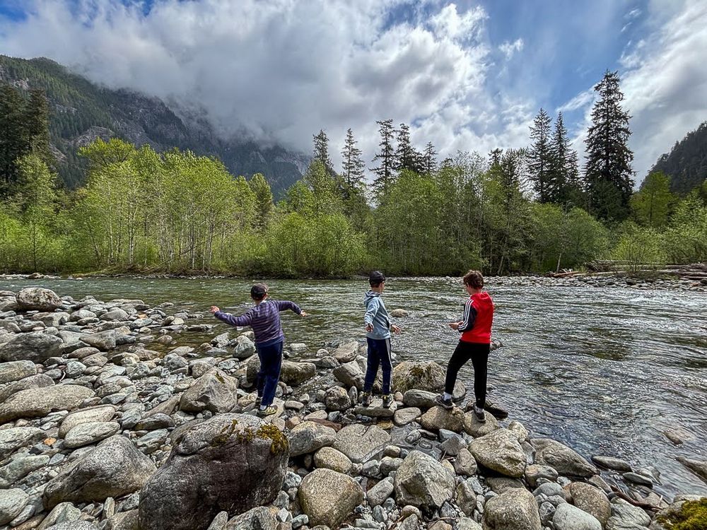 Three boys tossing rocks in the Taylor River below Garfield Mountain
