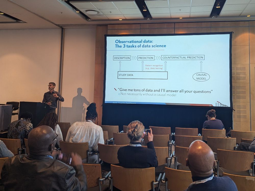 Photo of Miguel Hernan in front of a slide explaining the three tasks of data science