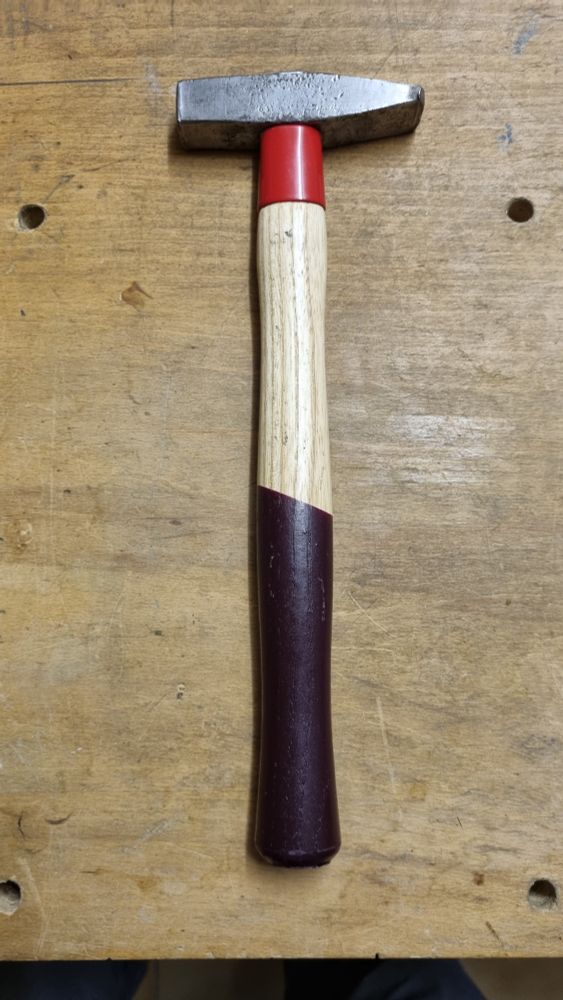 Ein kleiner 200 Gramm Schlosserhammer. Der Hammerkopf weist deutliche Gebrauchsspuren auf, der Holzstiel mit Schlagschutz ist nagelneu.