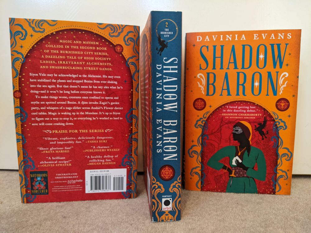A display of the back, spine and cover of Shadow Baron by Davinia Evans, showing the gorgeous orange, blue and red designs