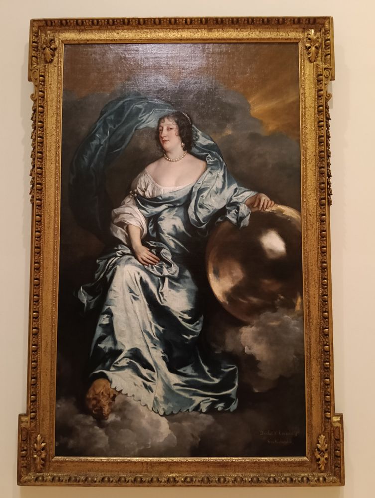 Photo of a massive and ornately framed portrait in oils, of a woman swathed in pale turquoise silk draperies, sitting casually against a stormy backdrop, with one arm resting on a massive orb and one foot propped on a skull. Her expression suggests she is not having any nonsense, thank you very much.