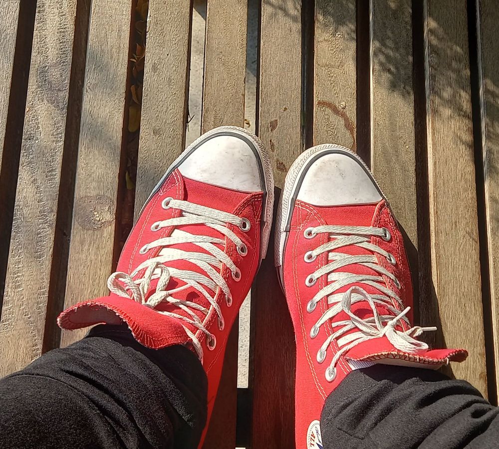 close up of Brie's red all stars while she sits on a porch