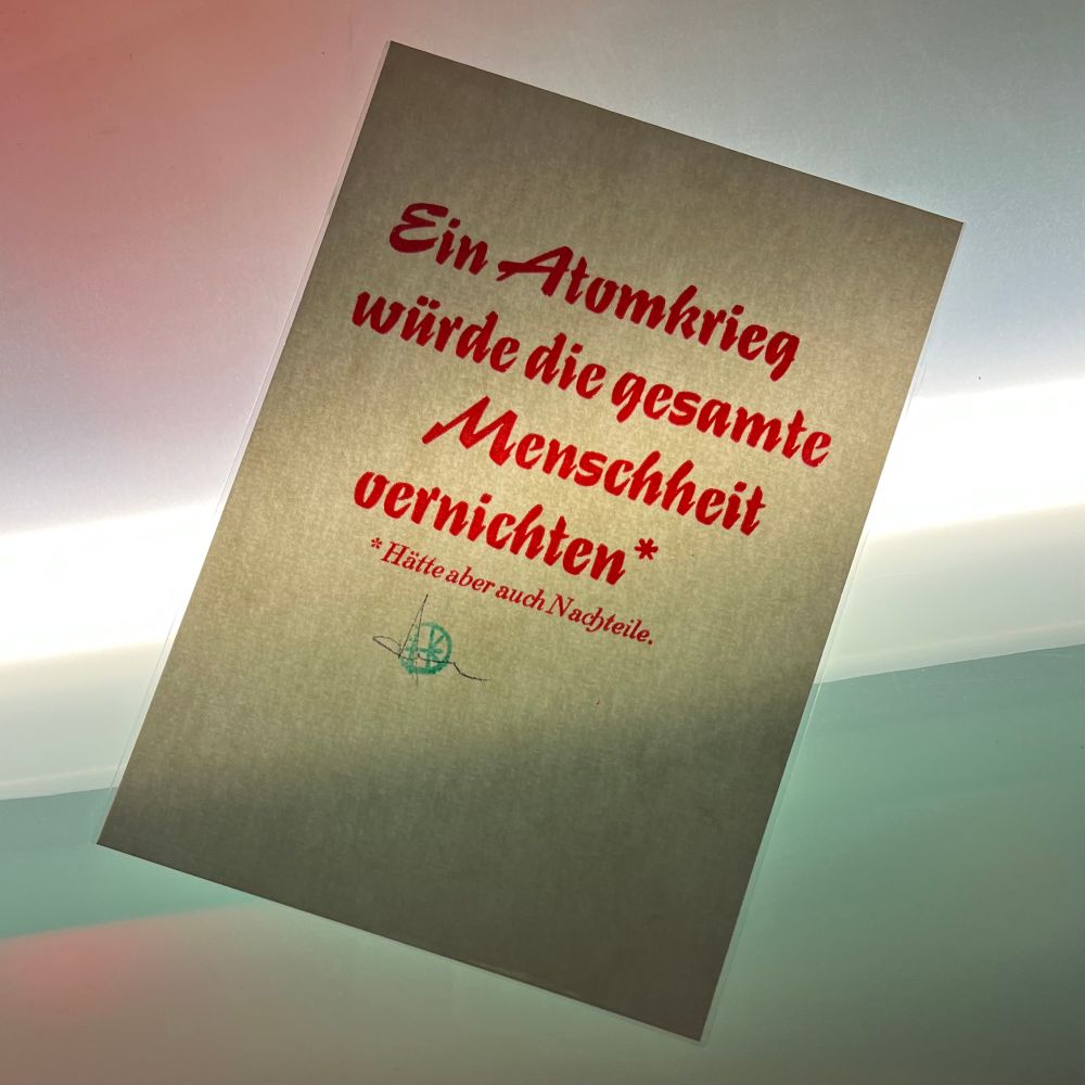 Gleicher Druck wie oben ausführlich beschrieben von Guido Kühn aus vorheriger Auflage. Es zeigt einen hellen Din A6 Karton mit roter Schrift und folgender Aussage:

‚Ein Atomkrieg würde die gesamte Menschheit vernichten.‘

Darunter steht in kleinerer Schriftgröße:

‚Hätte aber auch Nachteile.‘