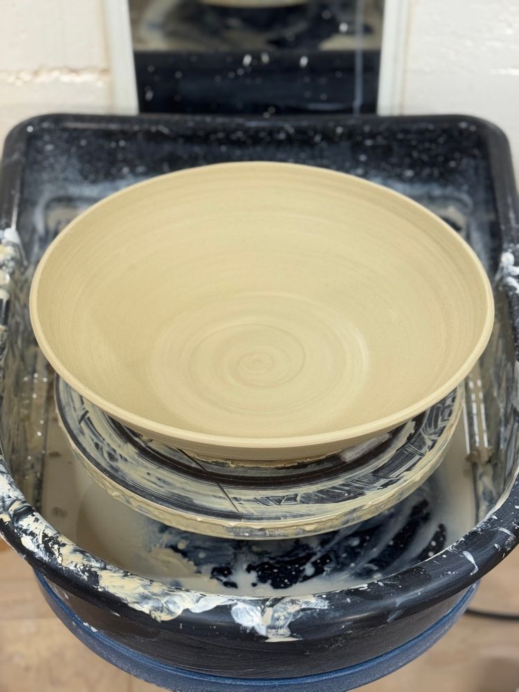 Big newly thrown wide shallow bowl still on the wheel