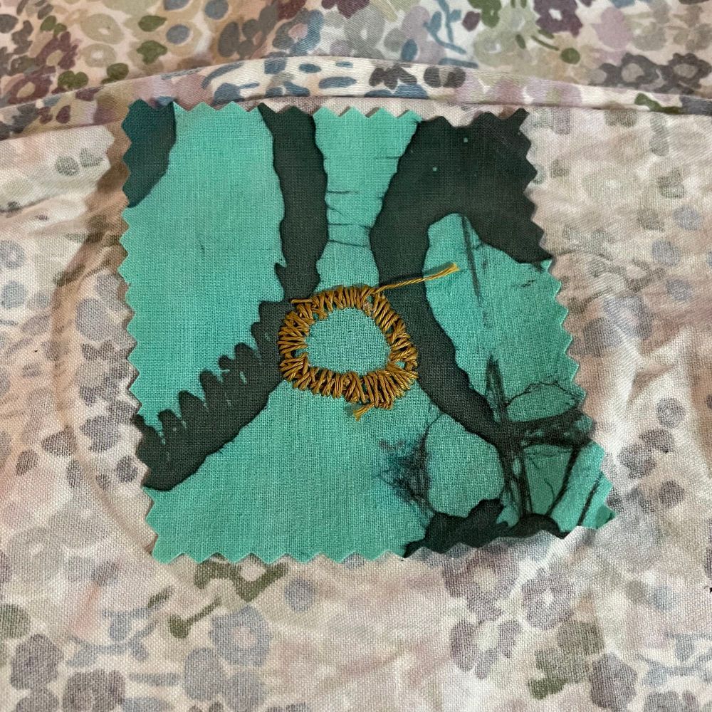 The not so pretty back of the work, the green stabilizing fabric has been cut away with pinking shears. The stitches are a little messier than the front side, but this is the backside of a satin stitch.