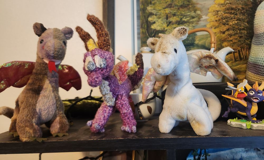 Photo of 4 dragon toys. A Scorch beanie baby, a handmade crochet Spyro from KrazyKariana, and a Magic beanie baby. And a spyro youtooz figure.