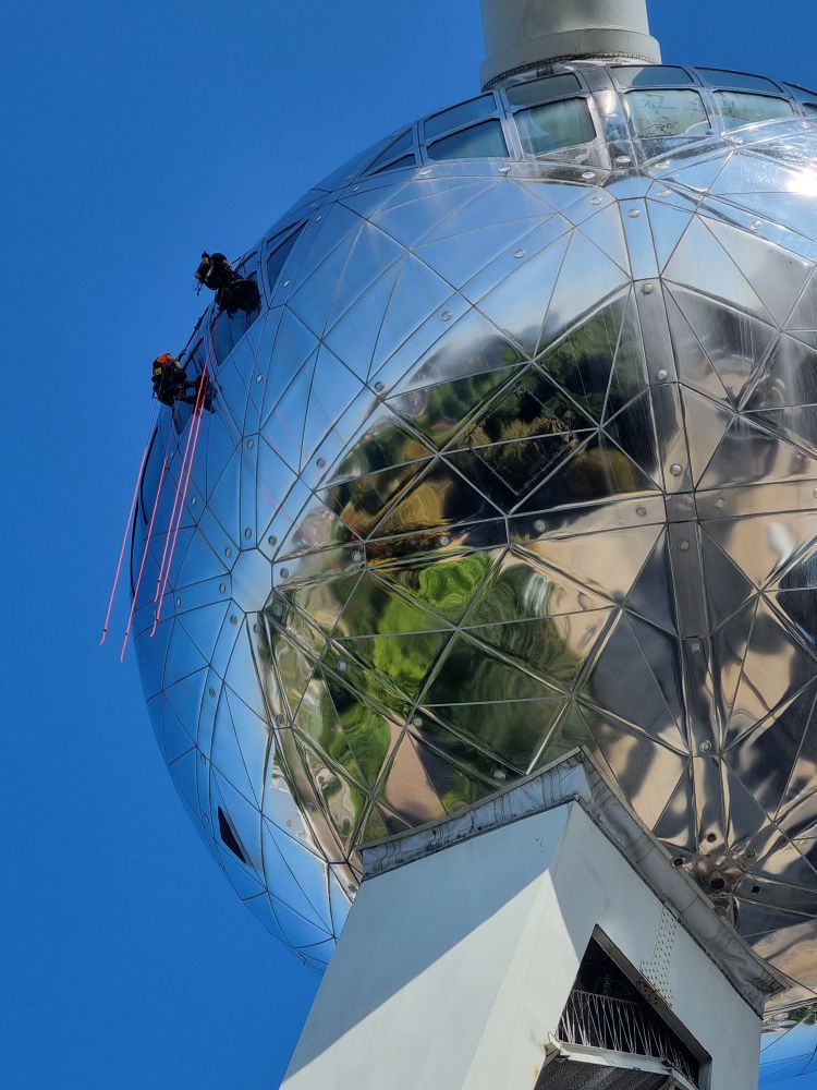 A close up of one atomium globe with 2 people climbing it.