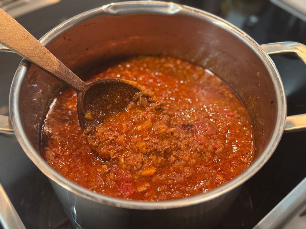 Nigella Lawsons Lasagne meat sauce stirred with a hand carved spoon