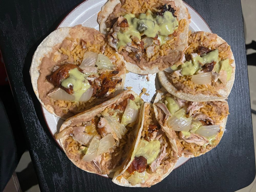 Showing a plate of six chicken tacos with onions and rice and beans with salsa Verde I made for Danny and I