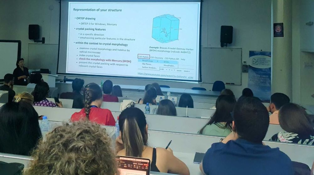 A presentation at the front of a room fill of people.