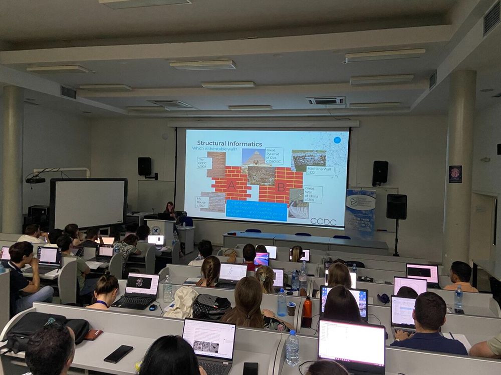 A presentation at the front of a room full of people with laptops.