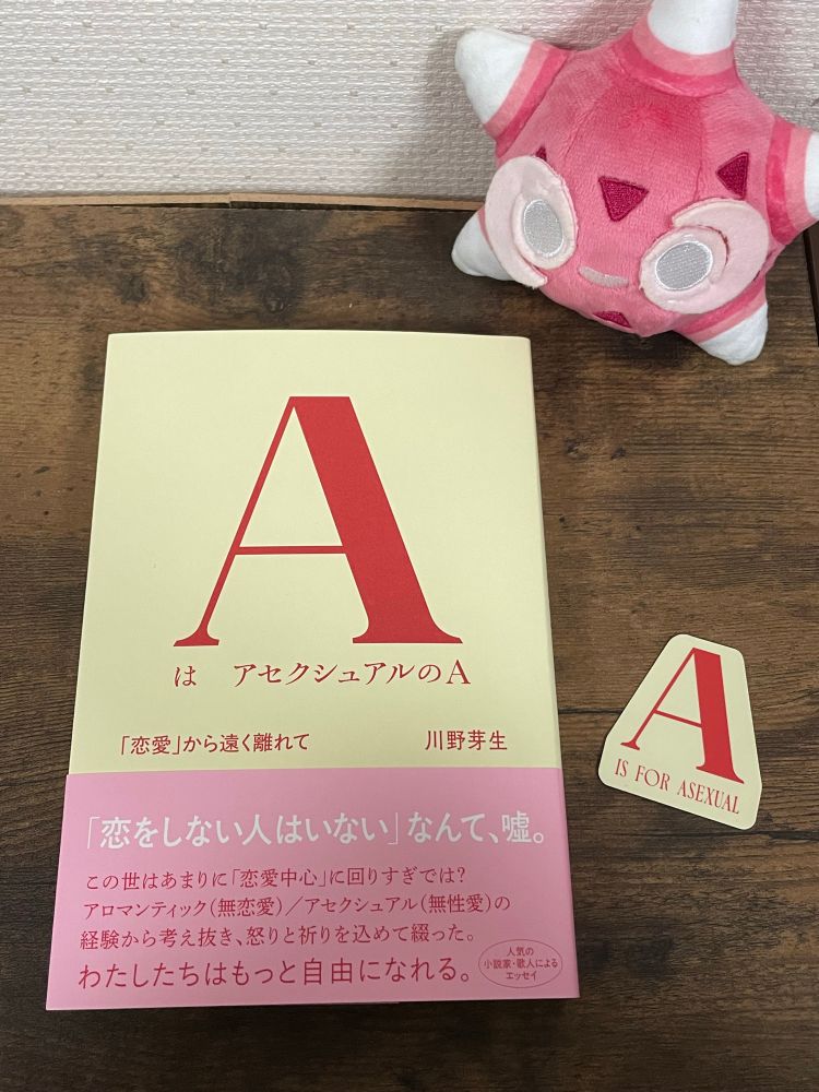 川野芽生著「AはアセクシュアルのA」という本と、その本の表紙と同じ「A」の文字を切り取ったステッカー(クリーム色の背景に赤い字でA IS FOR ASEXUALと書いてある)の写真。
その本を眺めるように、右上にポケモンfitのメテノのぬいぐるみがいる。