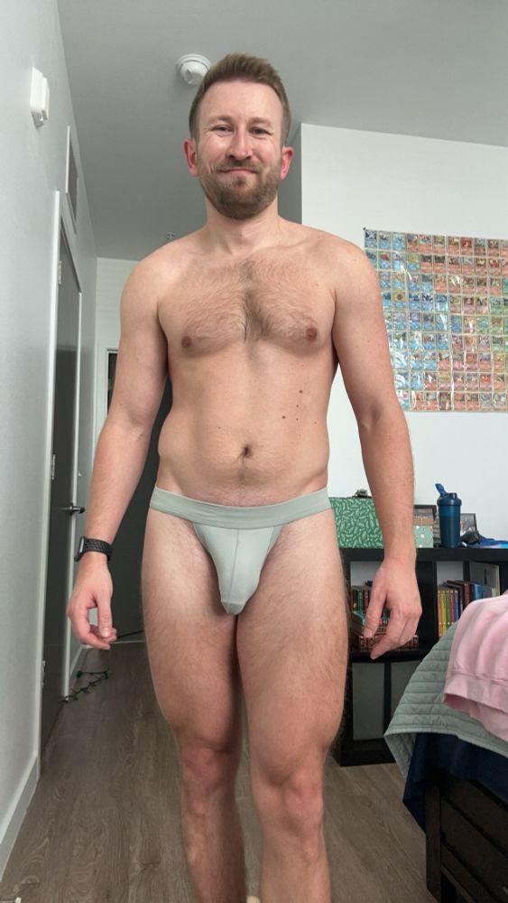 Man flexing his quads in a gray jockstrap