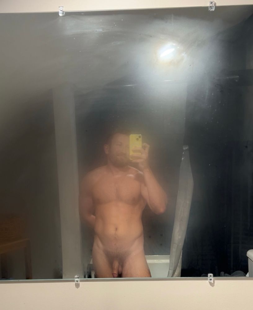 Mirror selfie of a nude man in a foggy bathroom mirror