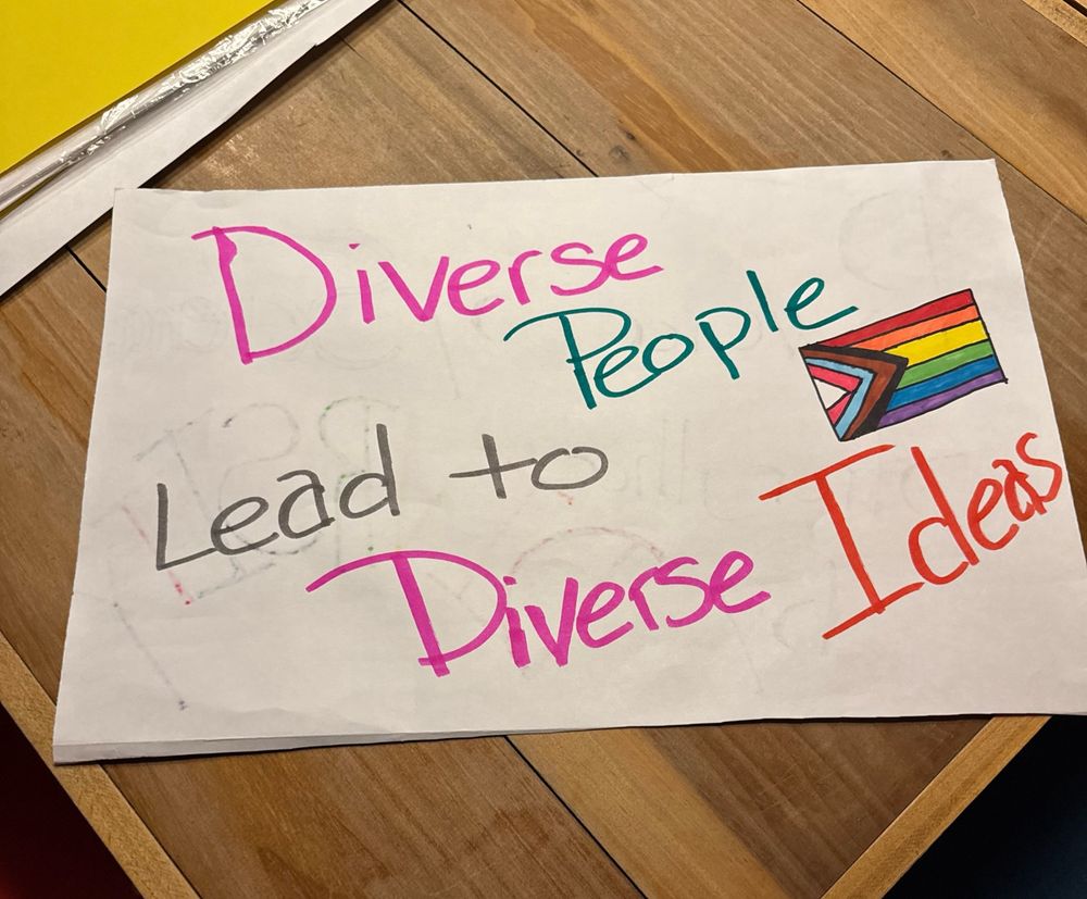 A sign reads Diverse People Lead to Diverse Ideas. Next to it is a pride flag drawing