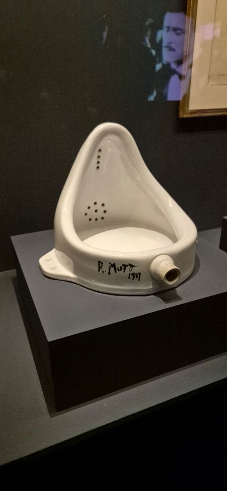 A replica of Marcel Duchamp's sculpture, Fountain, on a little podium behind glass