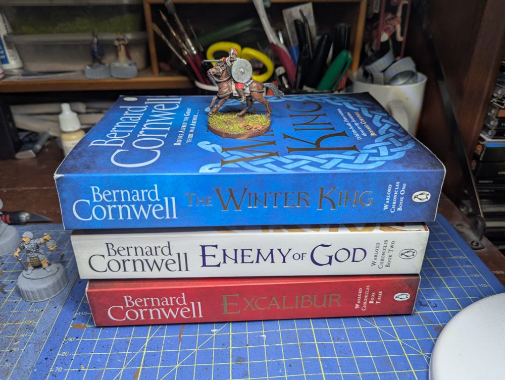 Bernard Cornwell's Warlord Chronicles series, with a wargames figure of Arthur atop them .