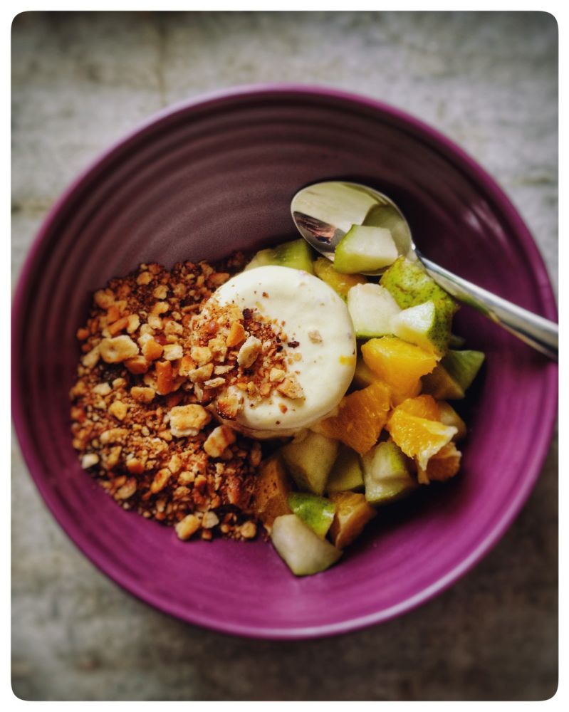 A bowl of ice cream with brown butter biscuit crumb and fruit salad.