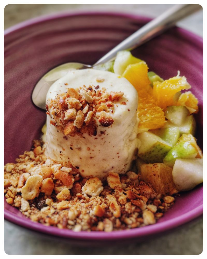 A bowl of ice cream with brown butter biscuit crumb and fruit salad.