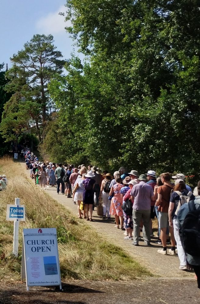 Long queue of people next to a signboard saying 