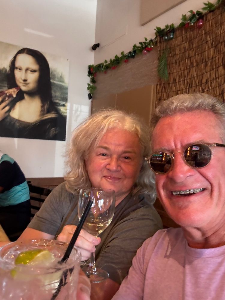 A woman and a man lifting their glasses for a toast and smiling.