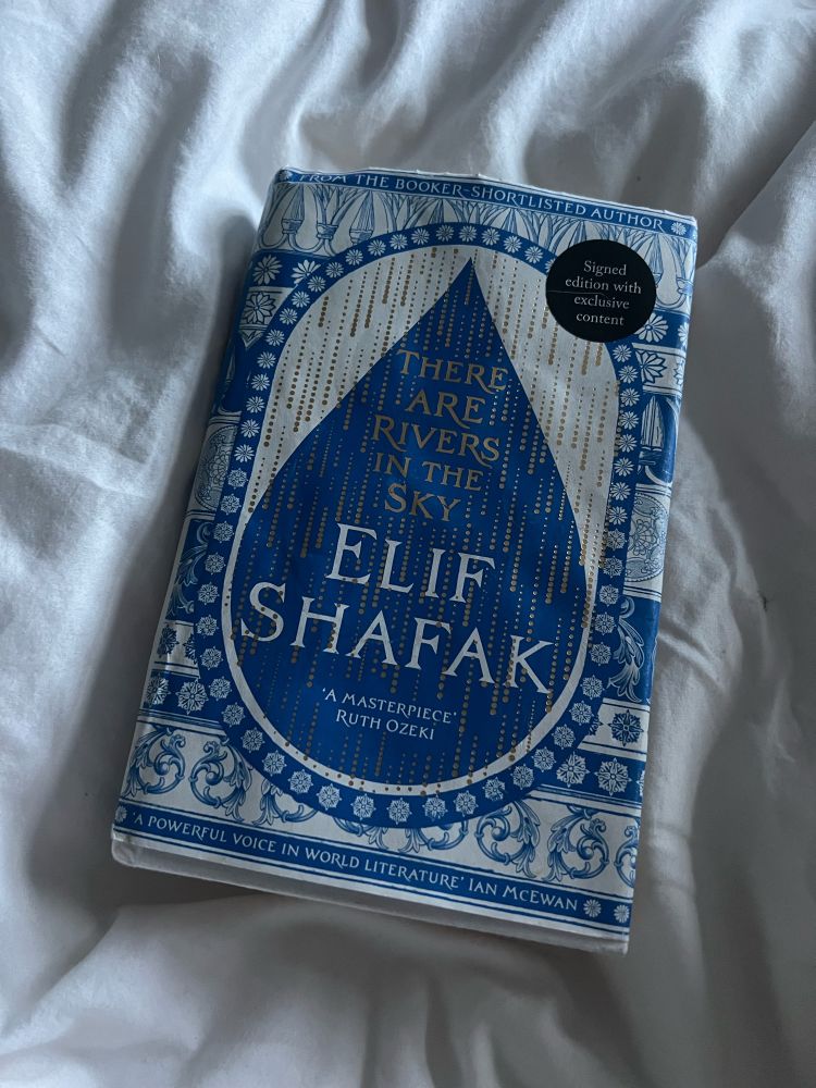 A picture of Elif Shafak’s latest book ‘there are rivers in the sky’ on a white bed sheet. The book cover is blue and white with a big water droplet 