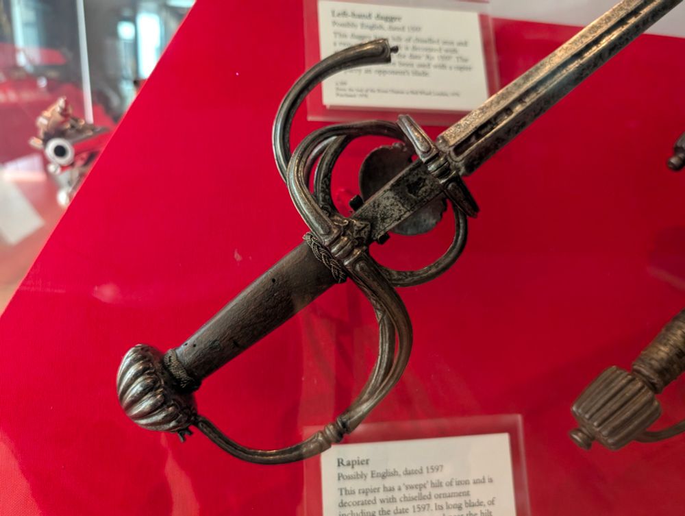 An antique rapier on a red background in the Royal Armouries Museum. 