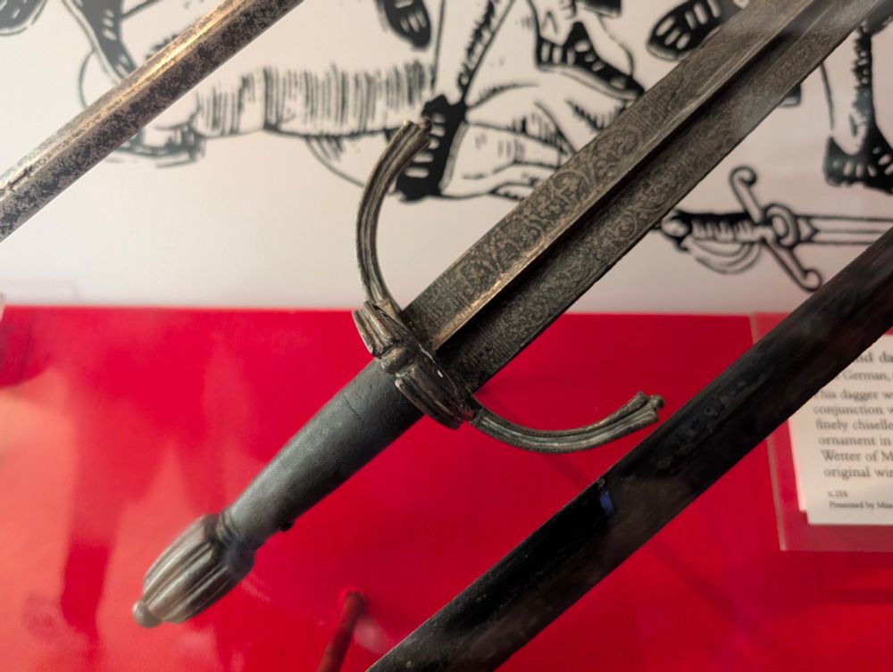 An antique dagger on a red background in the Royal Armouries Museum. 