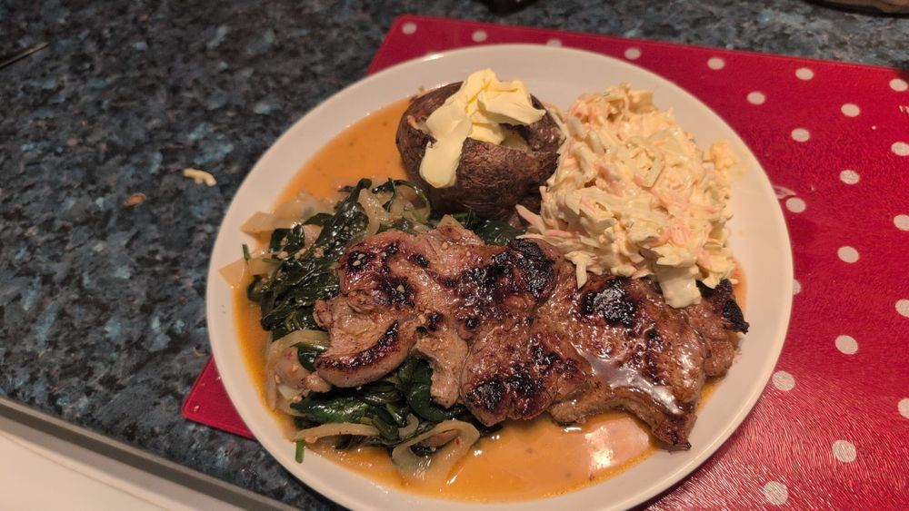 Plate of food with steak, baked potato, coleslaw, and a spinach and mushroom and onion mix in a Marsala wine sauce