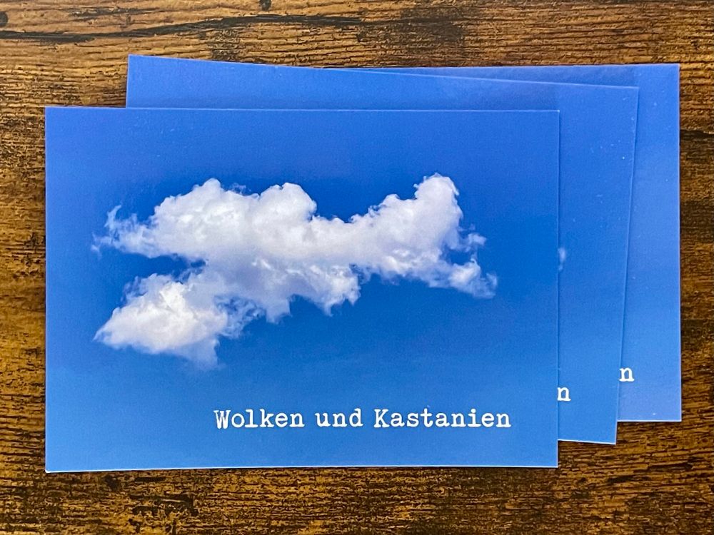 Postkarte mit einer weißen Wolke vor blauem Himmel und dem Schriftzug "Wolken und Kastanien"