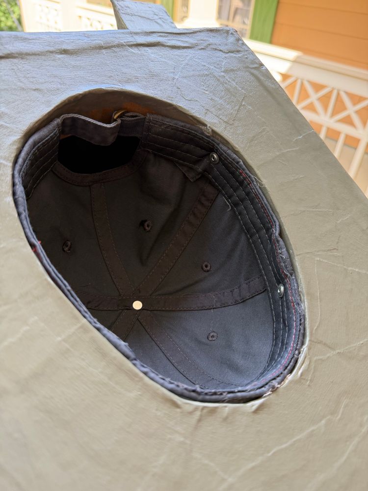 The bottom of the paper maché head, now painted grey and with a dark grey hat secured into the hole with pop rivets and hot glue.