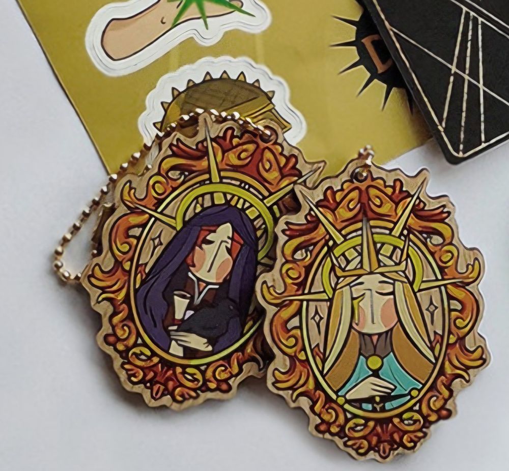 Wooden charm with golden frame with portraits of leliana on one side and andraste on the other 