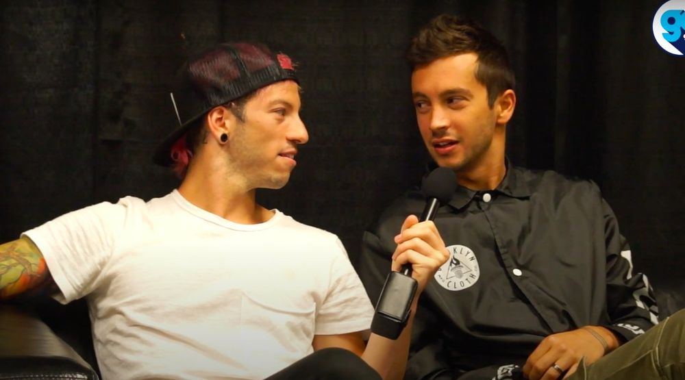 Joshua, white shirt and holding a mic towards Tyler, black jacket. eye contact goes crazy. 