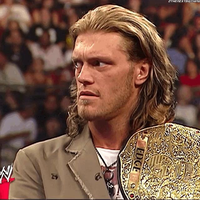 a man with long hair is holding a wrestling championship belt that says edge