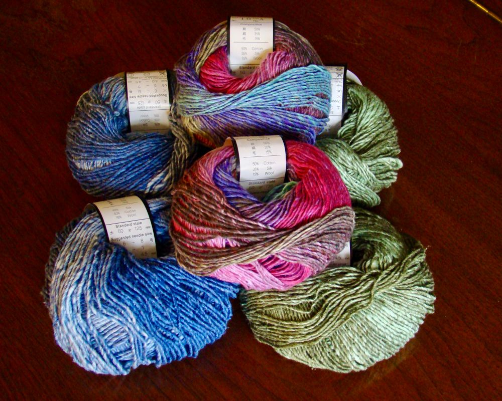 The six balls of Noro yarn that went into the shawl. Unfortunately, I didn’t think to turn one or more tags to show the name of the yarn, but you can read that it is a blend of 50% cotton, 35% silk, and 15% wool. There are two balls of each color way. From left to right, they are shades of blue, pinks and purples with a tiny bit of blue and green, and shades of mossy green.