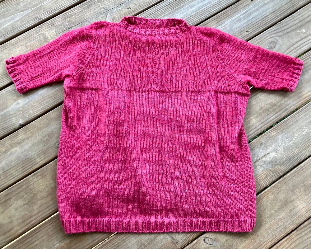 The back of my As If Lite Tee.  I don’t like wearing sleeveless or short sleeve tops, so I needed something other than the original cap sleeve design.  This was a bit tricky, because the top—at least the section where the two breast peaks are—has to be knit flat, and I don’t particularly like drop shoulders, so picking up sleeves from the cap ends wouldn’t work. I decided to put a centered seam in the middle of the back and to make the tops of set-in sleeves with decreases around the shoulders. Then I knit down from the armholes (which I provisionally cast on) until I had the length I wanted and finished with the cuffs.