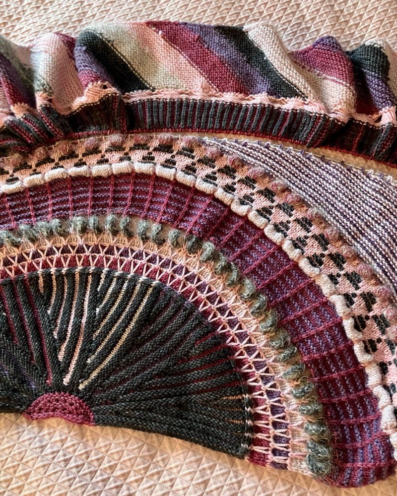 A closeup of the divided shawl, this time with the outer part flipped over the way I will sew it back on. I like it so much better this way! I will have to do a second cut, flip, and graft at the top so that the sections above the brioche are turned the right way again. 

The mohair I added is a sparkly lavender grey. I held it with the black for the i-cord spiral that looks like an old telephone cord, with the cherry in the line of bobbles, and with every sixth garter stripe in the border, so it cycles through all five yarn colors.