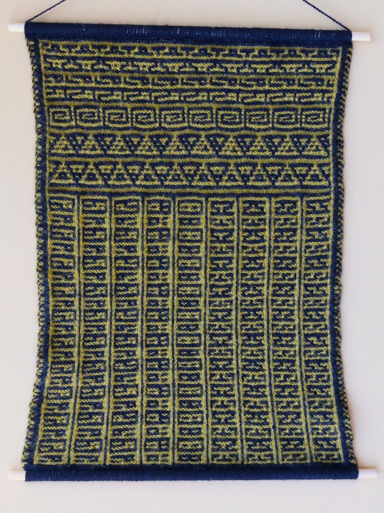 Float Free, Bumblebee (2018).  A tall rectangle of yellow and black knitting bound to wooden dowels at the top and bottom.  The wall hanging is divided into fourteen thin strips of various repeating patterns, a different pattern in each strip.  Five of these frieze patterns run across the top (along the knitting rows, the easier direction to knit).  The other nine are roughly the same length and run vertically side by side at the bottom of the fabric.  The fourteen designs look kind of like cartoon robot alien hieroglyphics.