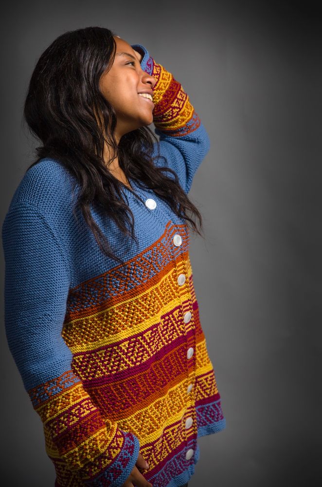Jasmine Long in a side view in the Seven Peaks Cardigan, smiling, with her left hand in her hair and her right arm hanging down. Both Jasmine and the photographer, Justin Forman, were very gracious with their time and their willingness to experiment with different poses and camera angles. This version of the cardigan was designed for a math fashion show, and so I kept it simple, but the version I made for myself has pockets! Working those in without disrupting the color patterns was a fun challenge. Assuming I ever manage to publish a pattern, I’ll definitely include the pocket option.