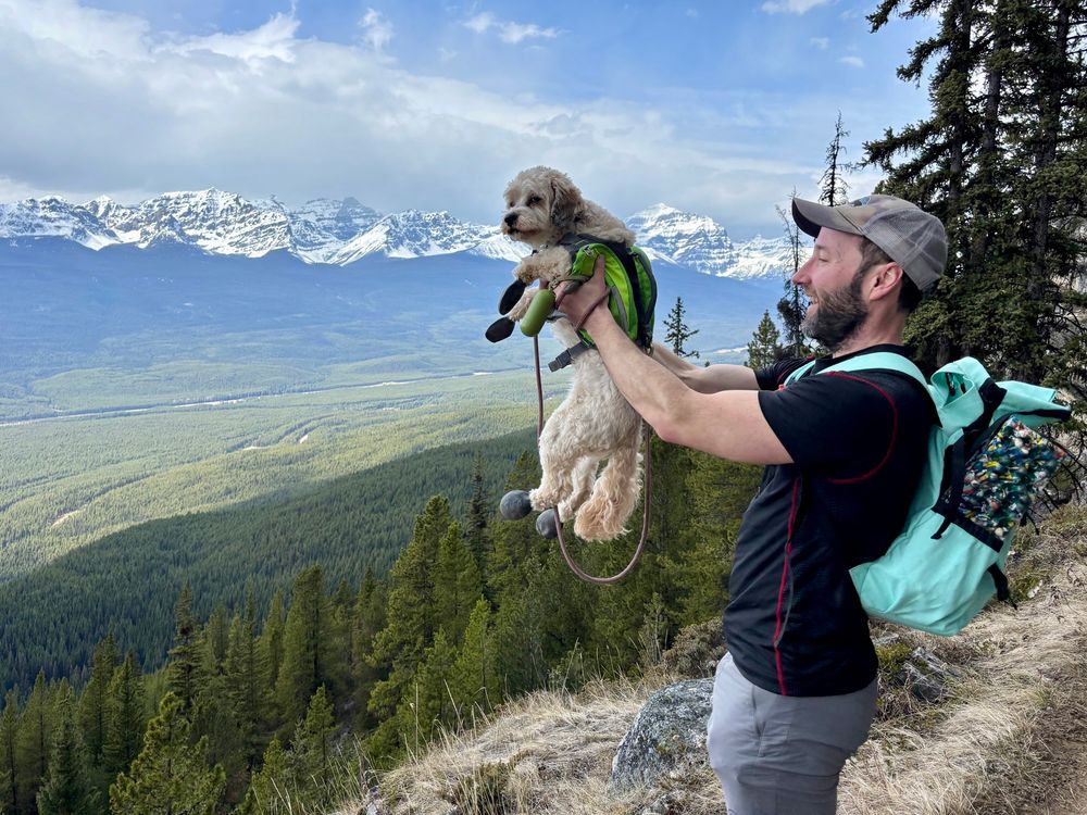 Guy holding dog overlooking a mountain view