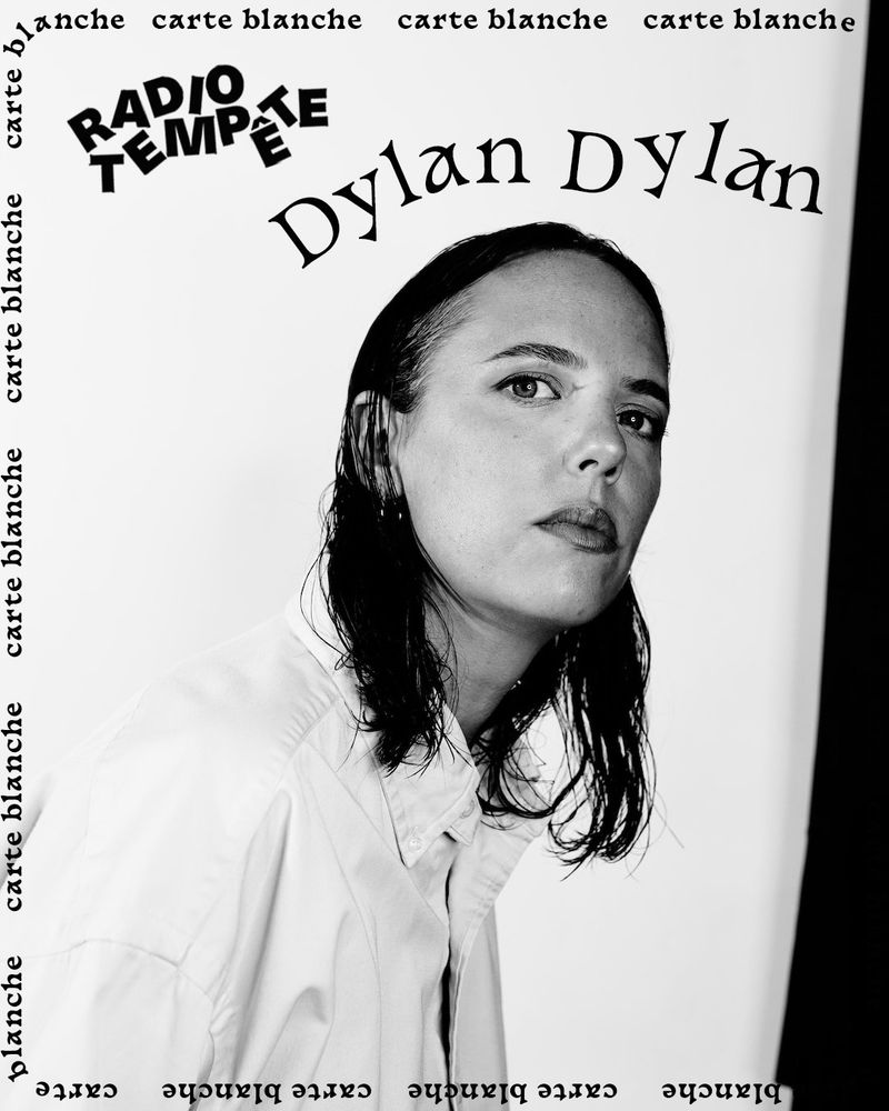Photo de l'artiste Dylan Dylan, en noir et blanc, cheveux mi longs, pose de profil, regarde l'objectif, chemise blanche. Au-dessus est écrit Radio Tempête Dylan Dylan 